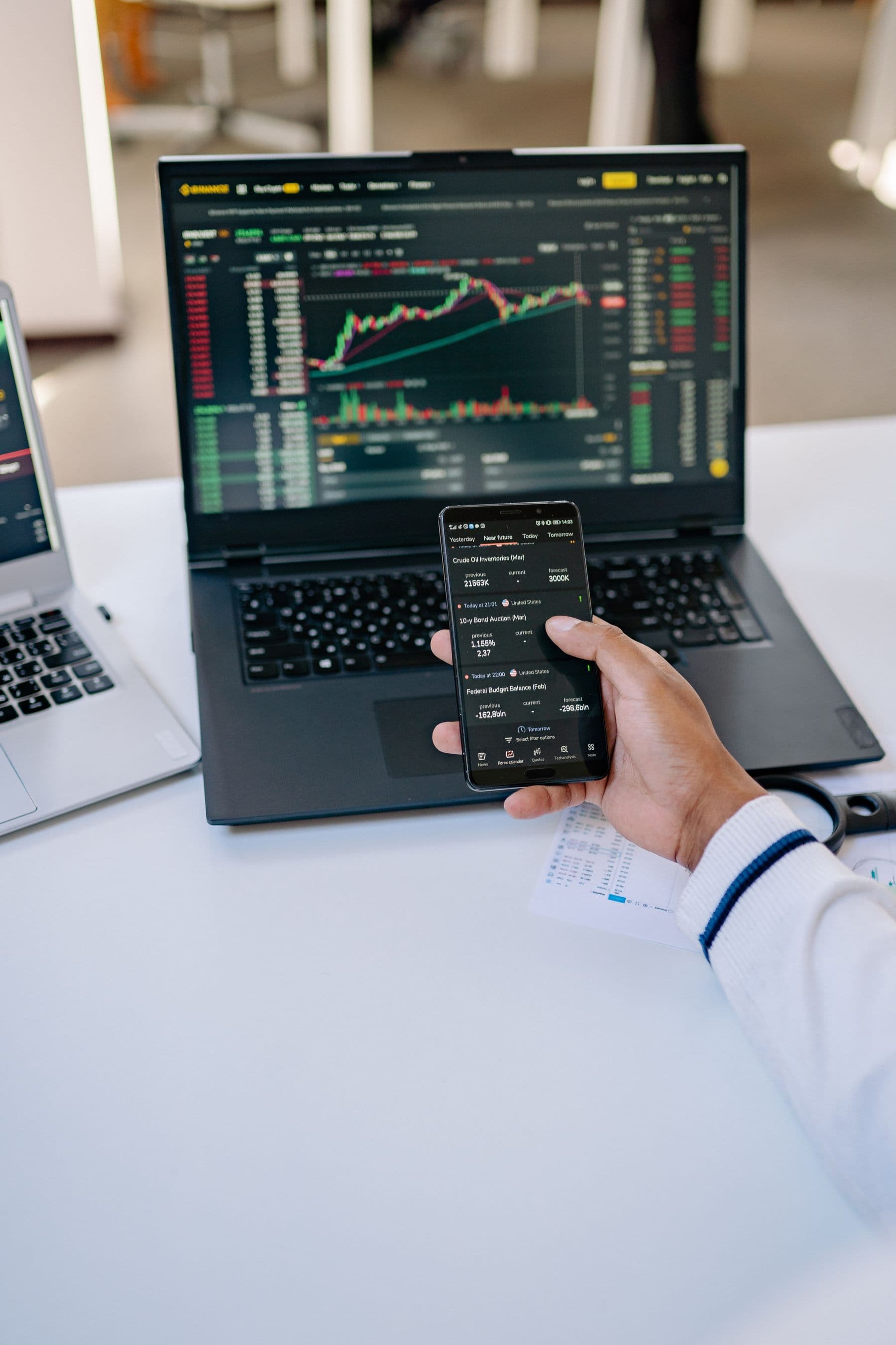 Teléfono y laptop mostrando información financiera en un espacio de trabajo