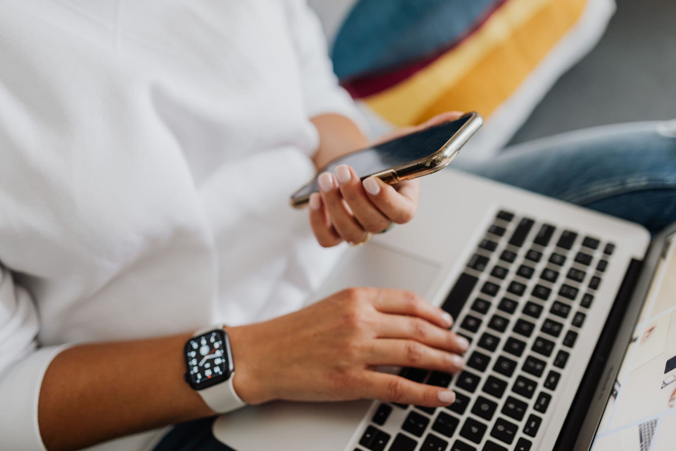 Persona revisando sus finanzas desde el teléfono junto a su laptop